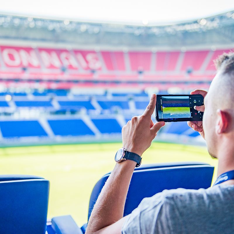 Supporteur prenant une photo du stade de l'Olympique Lyonnais.